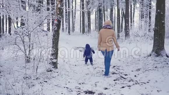 开朗一岁的男孩和母亲在冬天的森林里视频的预览图