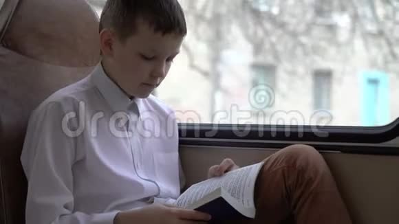 一个年轻的小学生坐公共汽车穿过城市读了一本书视频的预览图