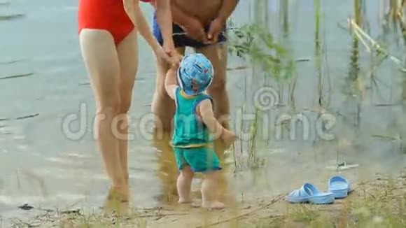 妈妈和爷爷在湖里和小男孩玩美丽的孩子在水中行走视频的预览图