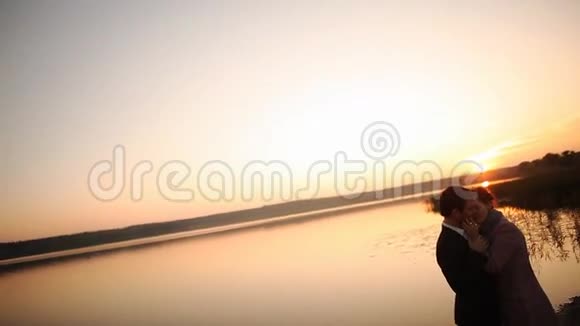 恋爱中的情侣在橘色夕阳下的背光剪影视频的预览图
