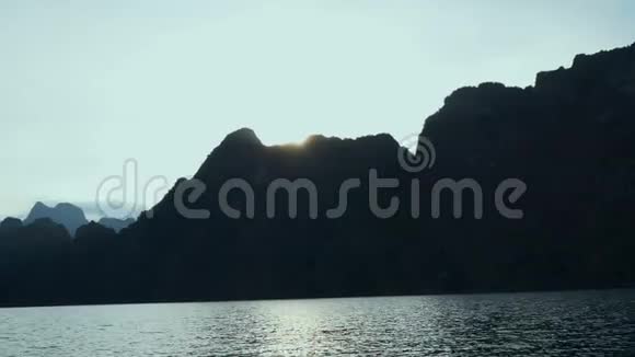 日落时乘船游热带湖水高山悬崖和岩石视频的预览图