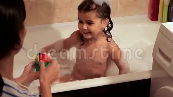 卷曲的女孩用泡沫洗澡在浴缸上画一支多色铅笔母女订婚了创造条件视频的预览图