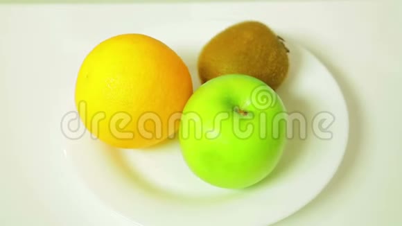 白色盘子上的橙色猕猴桃和绿色苹果旋转成一个圆圈视频的预览图