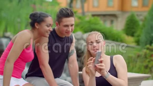多种族的人在公园里玩手机年轻的朋友视频的预览图