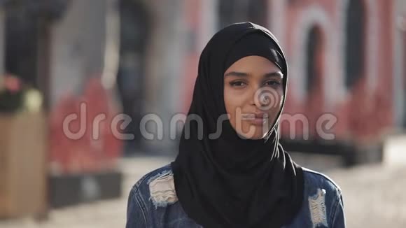 戴头巾的年轻美丽穆斯林女子的肖像注视着站在老城区的镜头视频的预览图