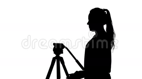 摄影师把相机放在三脚架上白色的剪影视频的预览图