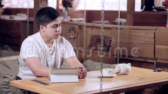 一个年轻人在咖啡馆里用平板电脑喝咖啡视频的预览图