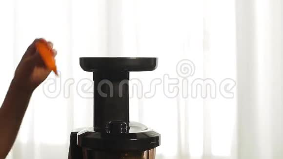 女人的手在榨汁机里加入胡萝卜视频的预览图
