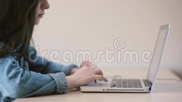 使用笔记本电脑的少女坐在家里的桌子上视频的预览图