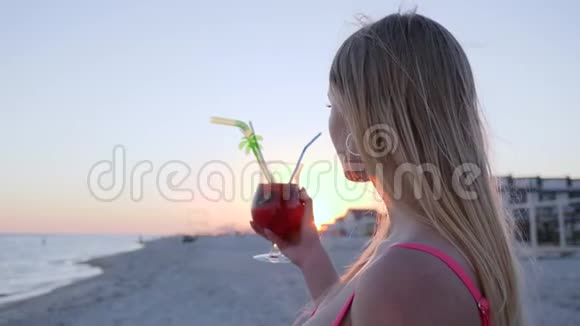 背光中的年轻女性肖像女孩喝鸡尾酒视频的预览图