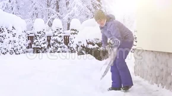 在大雪后年轻女子在房子附近铲雪视频的预览图