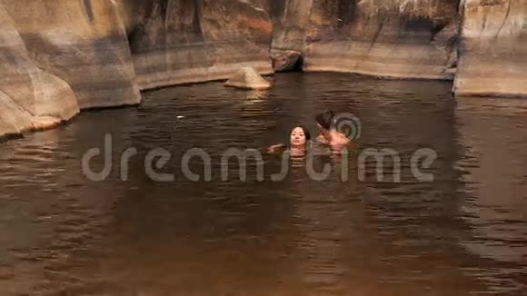 男孩抱着女孩在小溪创造的湖里游泳视频的预览图