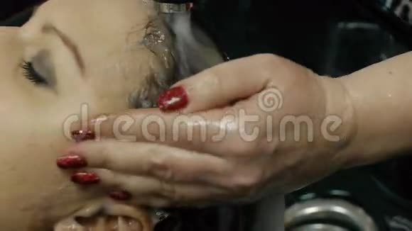 理发师在她的美发沙龙里用现代盆洗客户的头发视频的预览图