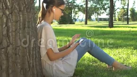 在公园里听音乐和使用智能手机的年轻女性视频的预览图
