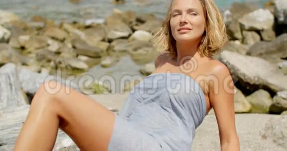 落基海岸线上裹着灰色布料的女人视频的预览图