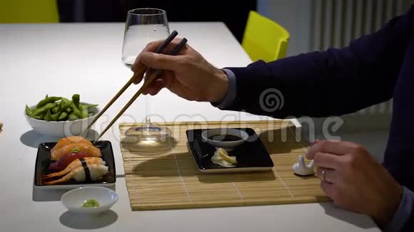 有胡子的男人在晚餐时吃寿司和喝白葡萄酒的慢动作视频视频的预览图