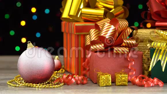 漂亮的圣诞礼物盒和装饰在木地板上五颜六色的闪光花环在黑色无缝循环视频的预览图