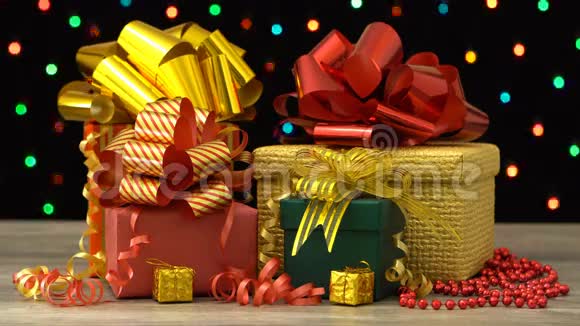 漂亮的圣诞礼物盒和装饰在木地板上五颜六色的闪光花环在黑色无缝循环视频的预览图