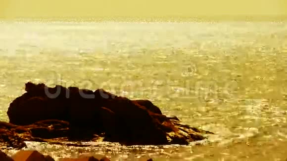 闪闪发光的水面和岩石礁海岸地平线天际线日出黄金视频的预览图
