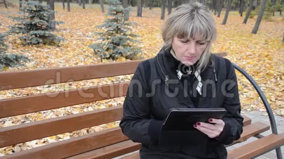 秋天公园里的女人在用平板电脑视频的预览图