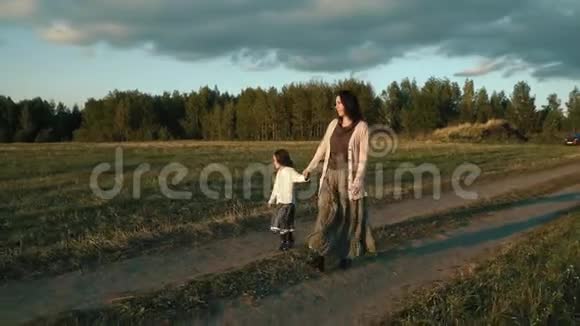 母亲带着女儿在夕阳下走在农村的路上视频的预览图