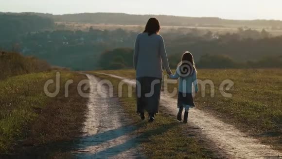 母亲带着女儿在夕阳下走在农村的路上视频的预览图