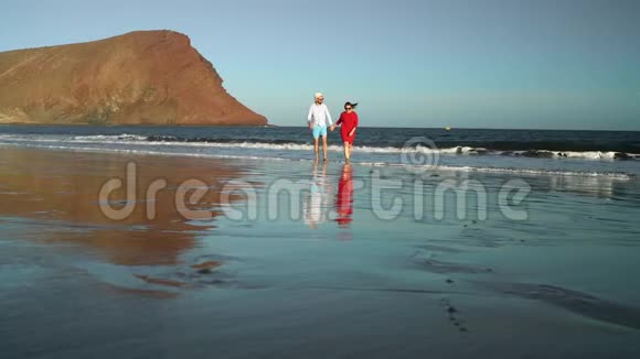 恋爱中的夫妻无忧无虑地从海滩上的水中散步加那利群岛特内里费海岸图片视频的预览图