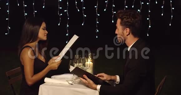 年轻浪漫的情侣在看菜单视频的预览图