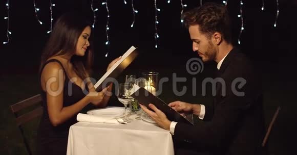 年轻浪漫的情侣在看菜单视频的预览图