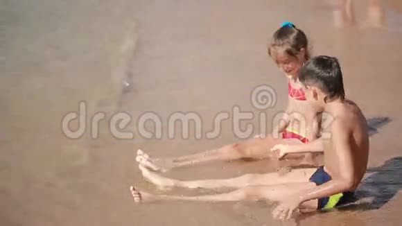 孩子们男孩和女孩在海滩上玩沙子建造一座沙堡视频的预览图