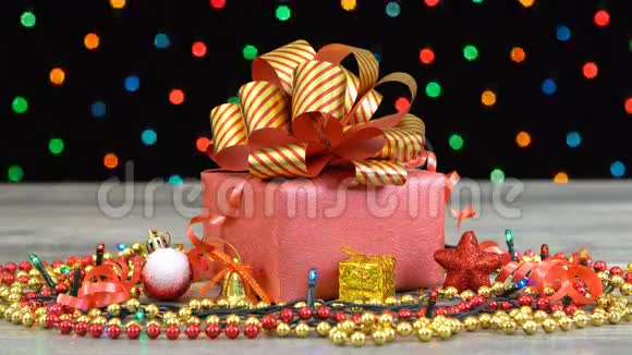 漂亮的圣诞礼品盒上面有红色和金色条纹的蝴蝶结木地板上有装饰五颜六色的闪光视频的预览图