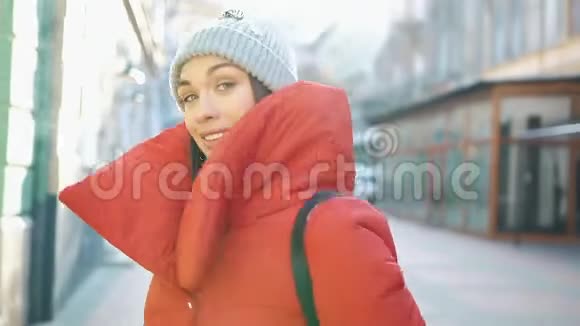 在一个美丽的欧洲老城区穿着红色冬装的美丽女子沿着白雪覆盖的街道散步视频的预览图
