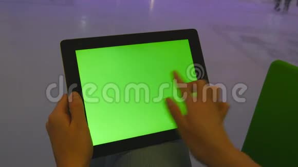 女性手使用平板电脑与绿色屏幕在购物中心很多人在室内冰场溜冰视频的预览图