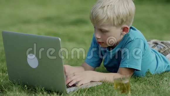 在草地上用笔记本电脑的男孩视频的预览图
