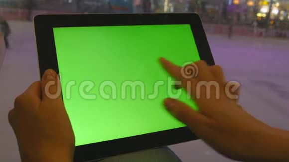 女性手使用平板电脑与绿色屏幕在购物中心很多人在室内冰场溜冰视频的预览图