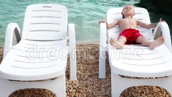 小男孩穿着白色的躺椅在海边漫步视频的预览图