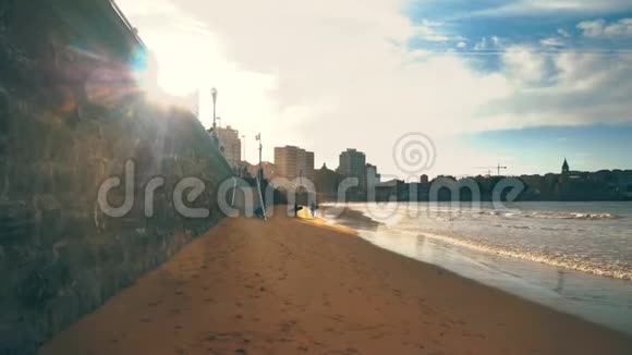 令人惊叹的金色光城堤日落与步行放松的人城市建筑和海浪在美丽的l视频的预览图
