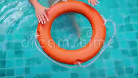 女性手在蓝水池中触摸和扭曲救生圈视频的预览图