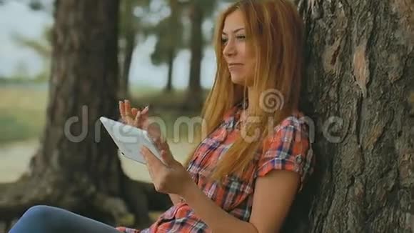 有平板电脑的女孩坐在森林里户外慢动作视频的预览图