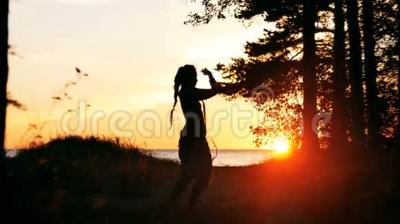 日落时跳舞的年轻女子剪影视频的预览图