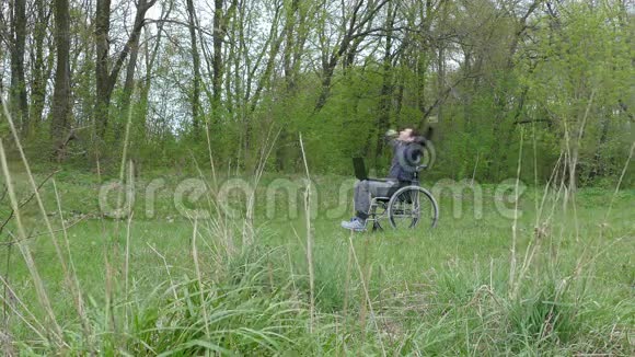 残疾人惊喜成功胜利轮椅带手提电脑坐在轮椅上工作自然绿色背景视频的预览图
