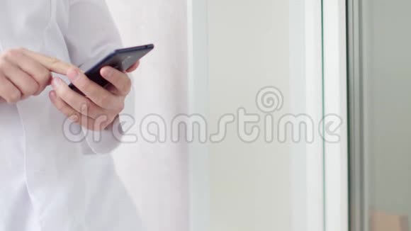 身穿白大褂的男医生用的是带有触摸屏的现代智能手机视频的预览图