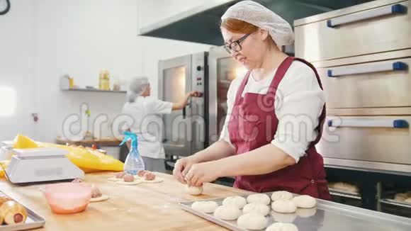 戴眼镜和围裙的女人在面包店里做蛋糕视频的预览图