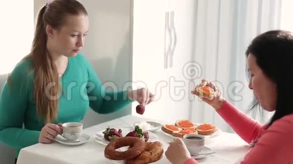 早餐两个年轻女人年轻的女人喝咖啡说话两个年轻女人在早餐时的谈话视频的预览图