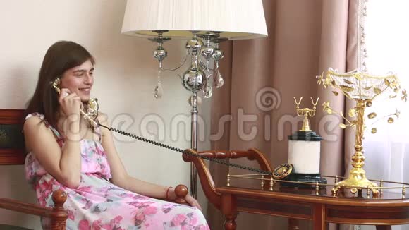 年轻漂亮的女人坐在椅子上打着老式电话视频的预览图