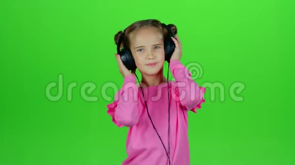 孩子听耳机里的音乐绿色屏幕慢动作视频的预览图