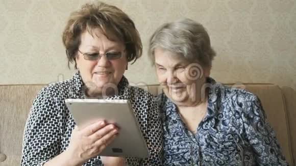 两个女人用电子平板电脑看照片视频的预览图