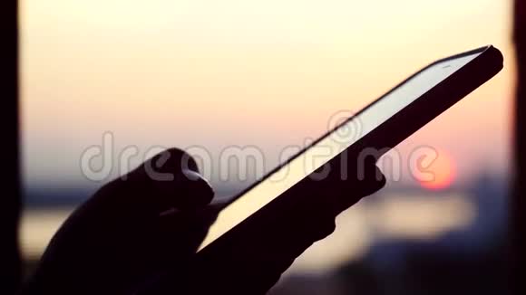 在夕阳和城市的背景下女人手拿着手机3840x2160视频的预览图
