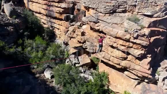 男子乘坐绳索在岩石山脉上行走4k视频的预览图
