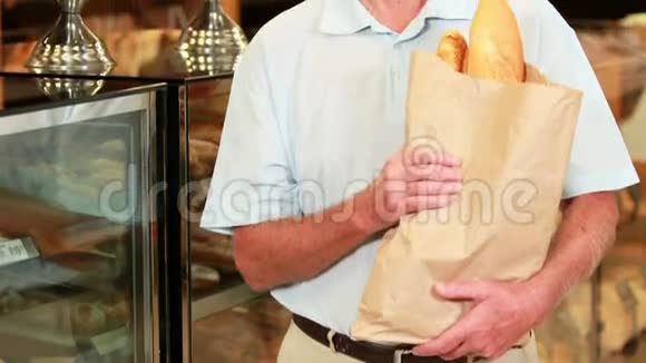 超市里拿着小面包的老人视频的预览图